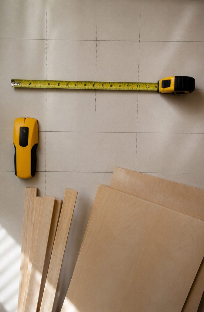 A measuring tape and pencil on a closet floor for shelf planning.
