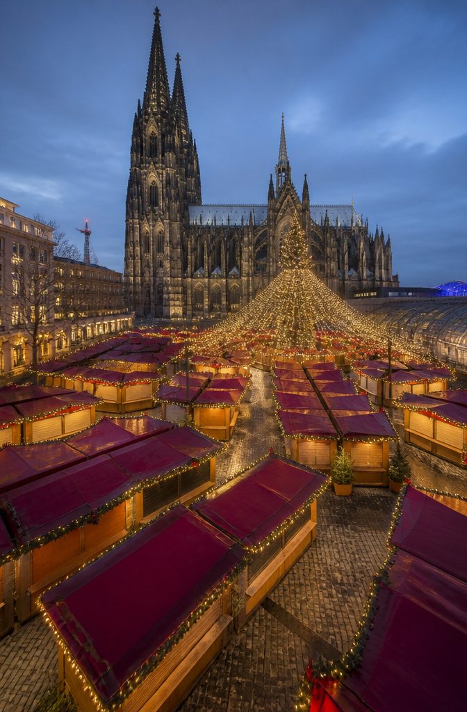 Where to Spend the Holidays: 14 Destinations for 2026 9 Christmas market in Cologne with stalls and Cologne Cathedral in the background.